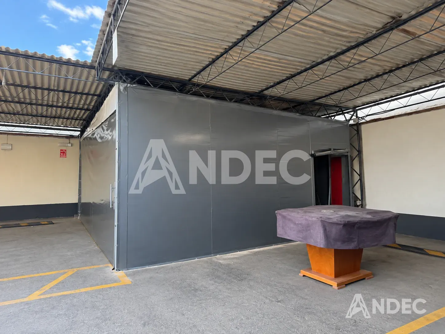 Frente del almacén cerrado en lona PVC aluminizada, con la puerta enrollable para el personal