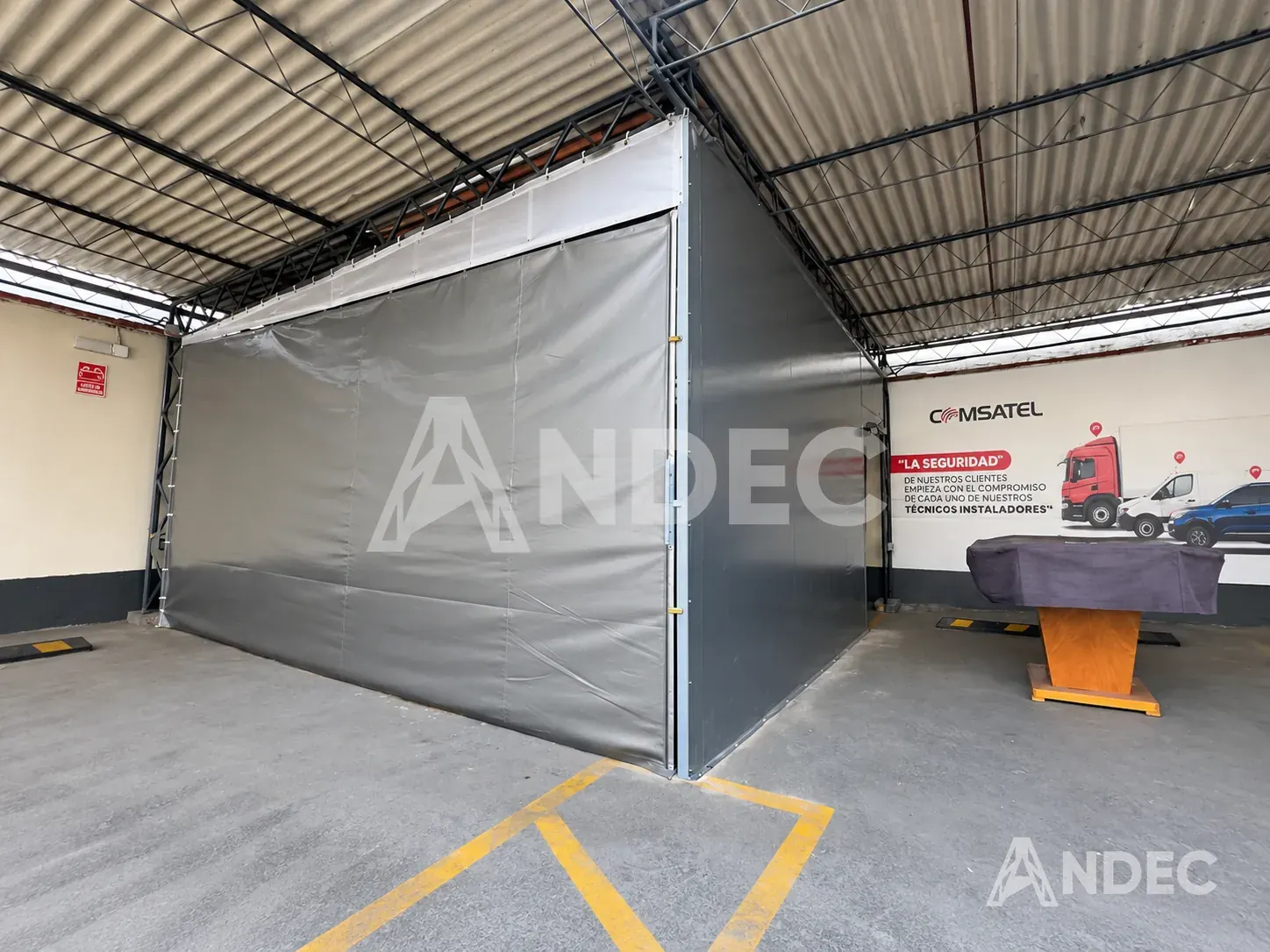 Lateral del almacén en lona PVC aluminizada junto a la señalética de seguridad de Comsatel