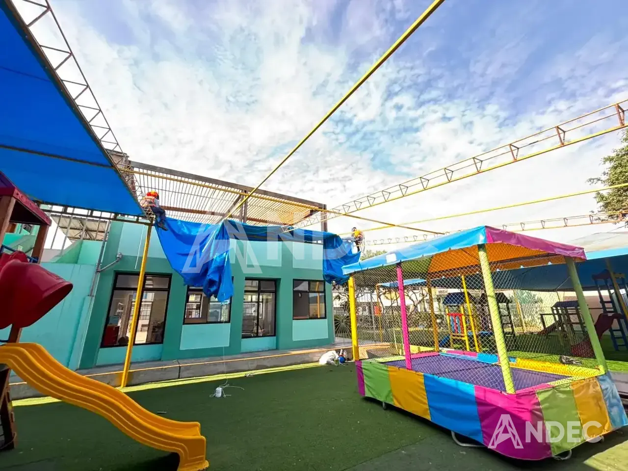 Operarios de ANDEC tensando la lona PVC azul sobre el patio de juegos del colegio
