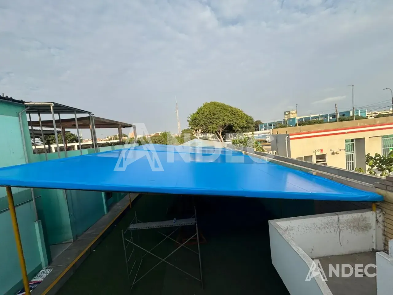 Cobertura de lona PVC azul del patio escolar vista desde la azotea, ya tensada sobre la estructura