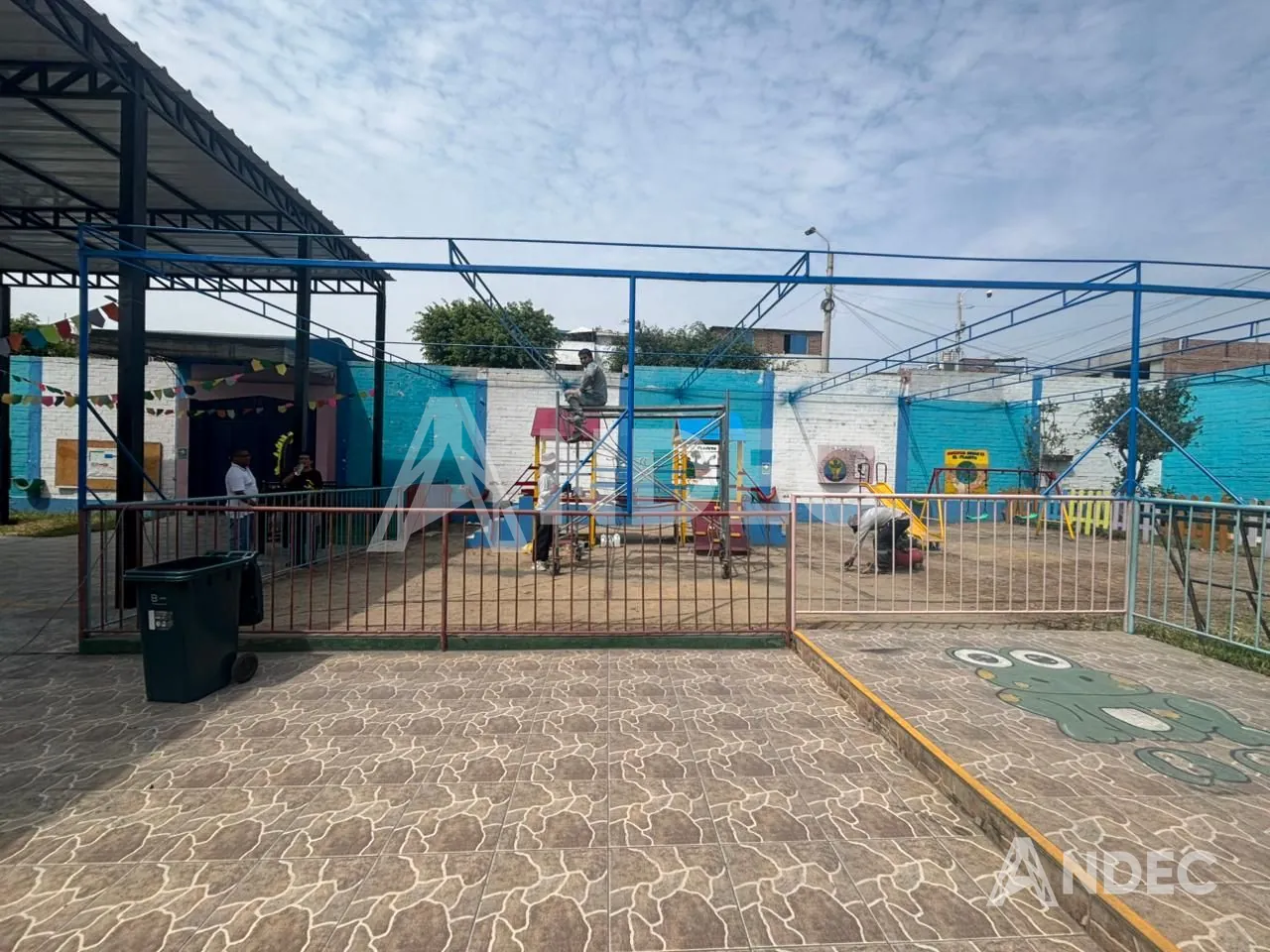 Estructura metálica sobre el patio de juegos del colegio, con los juegos infantiles debajo