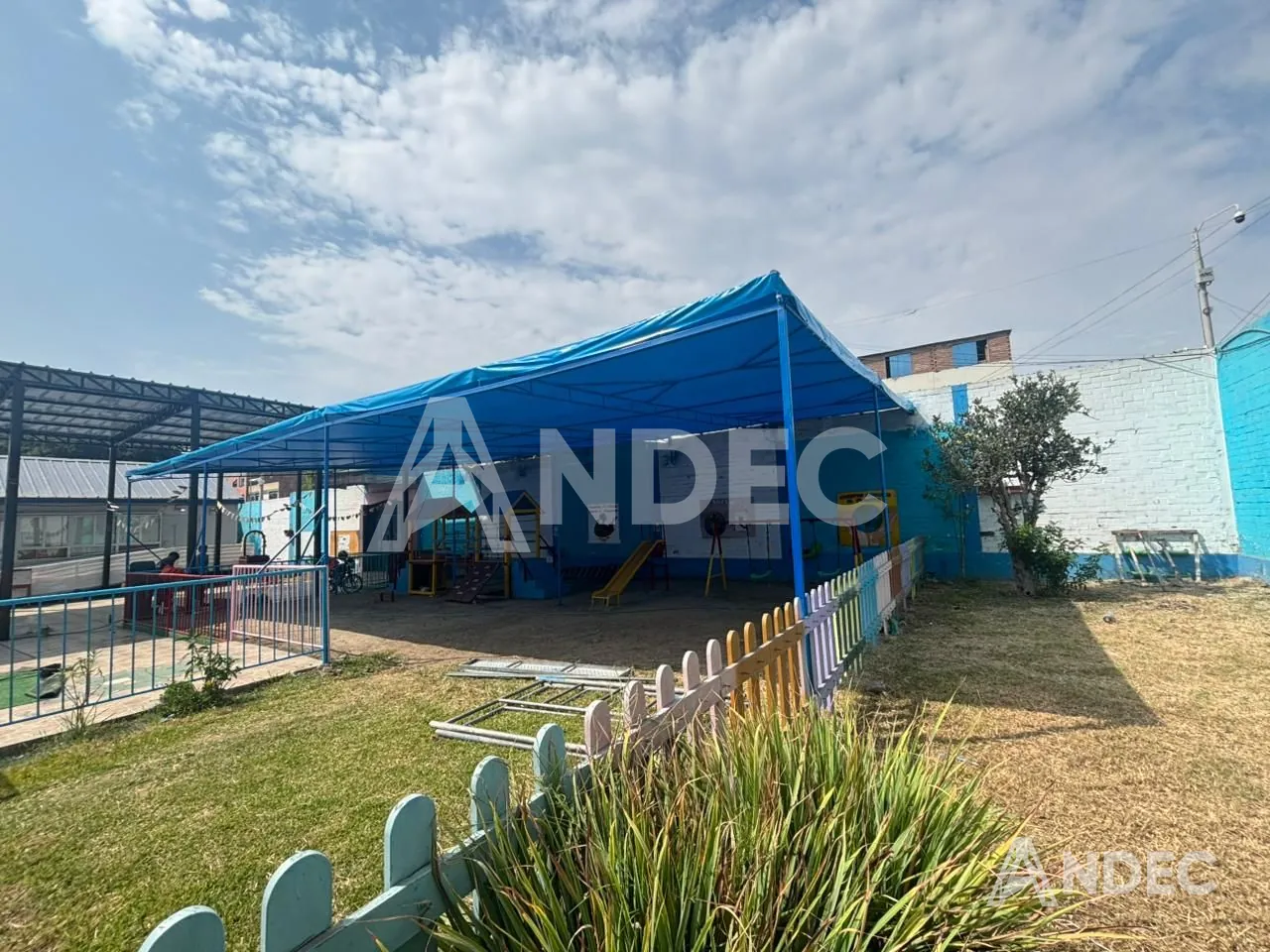 Cobertura del patio escolar en lona PVC azul vista desde el jardín del colegio