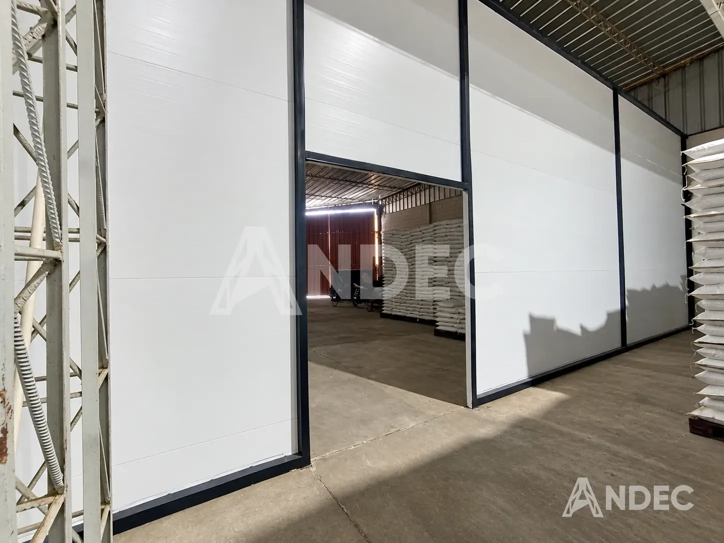 Vano de puerta abierto en la pared de lona PVC blanca, con el almacén de sacos al otro lado