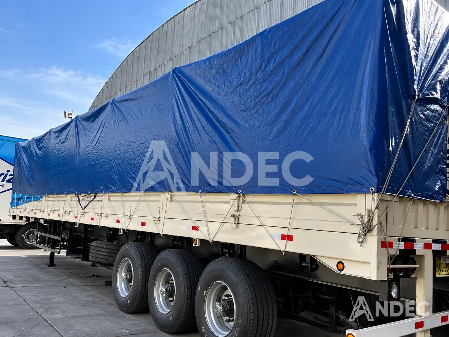 Carga de camión cubierta con manta de tarflex azul de 200 gr/m², amarrada por los ojales