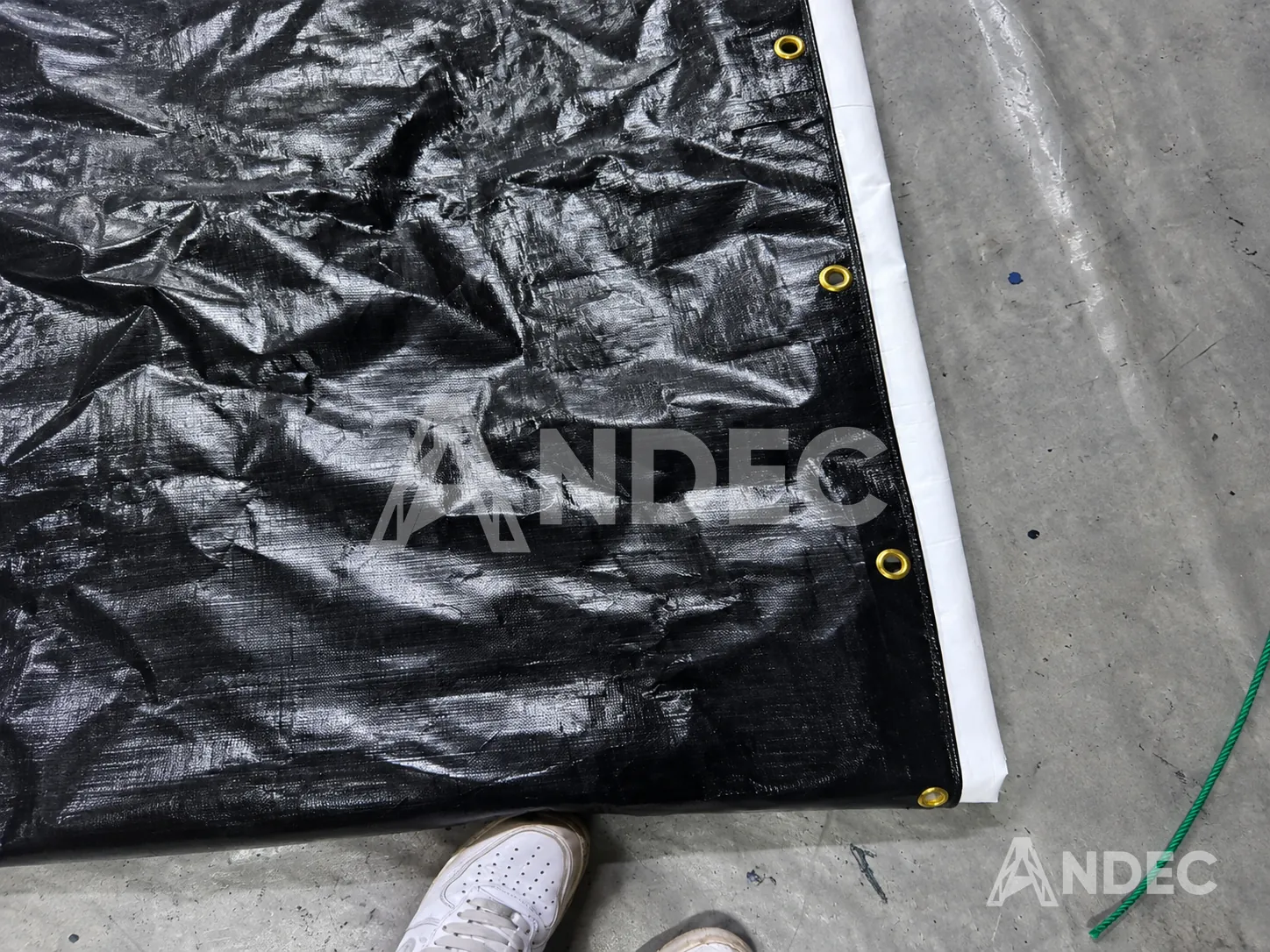 Detalle de manta de tarflex negra de 300 gr/m² con ojales metálicos y borde reforzado