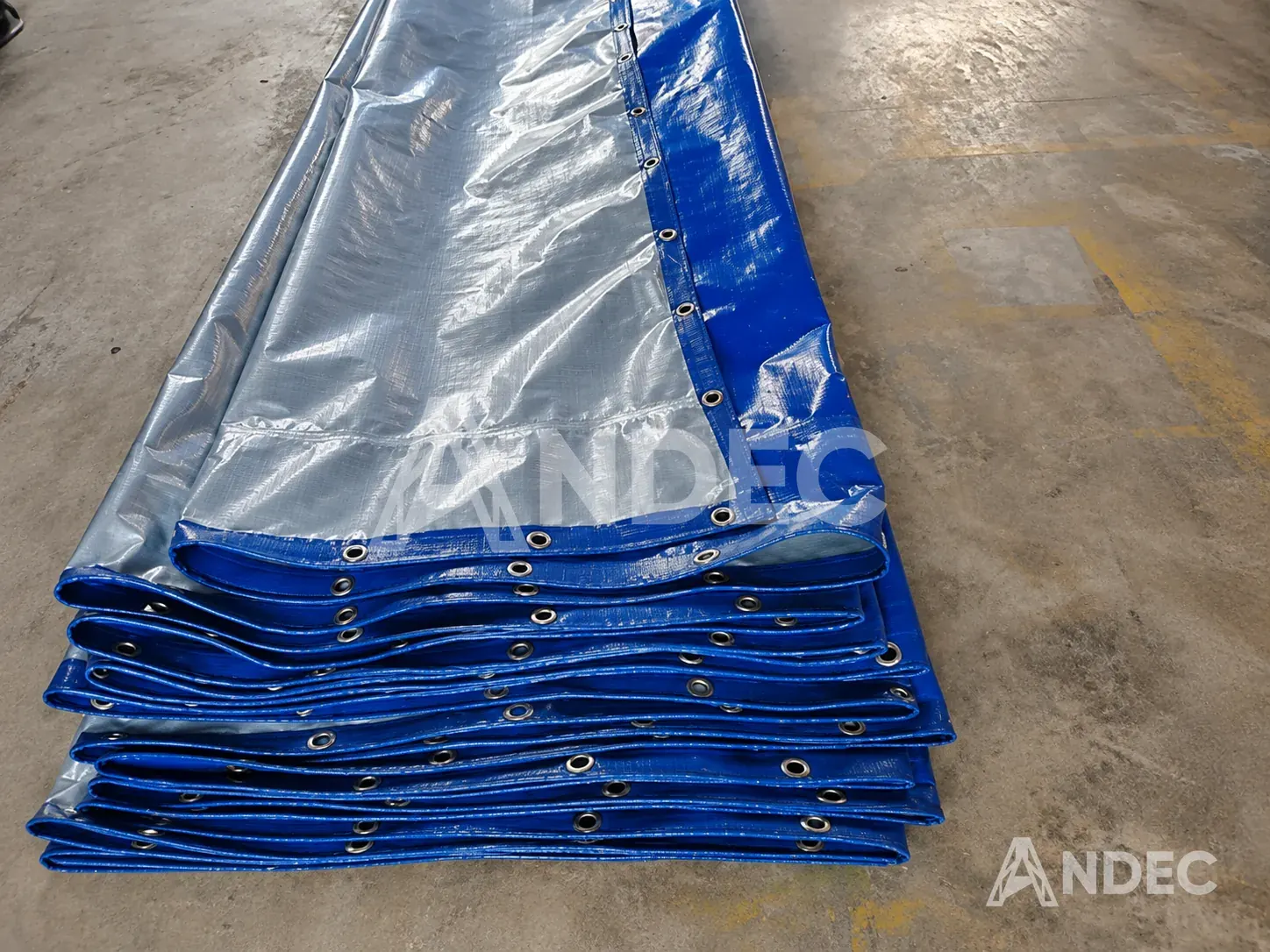 Ojales metálicos y borde reforzado de una manta de tarflex azul/plata plegada
