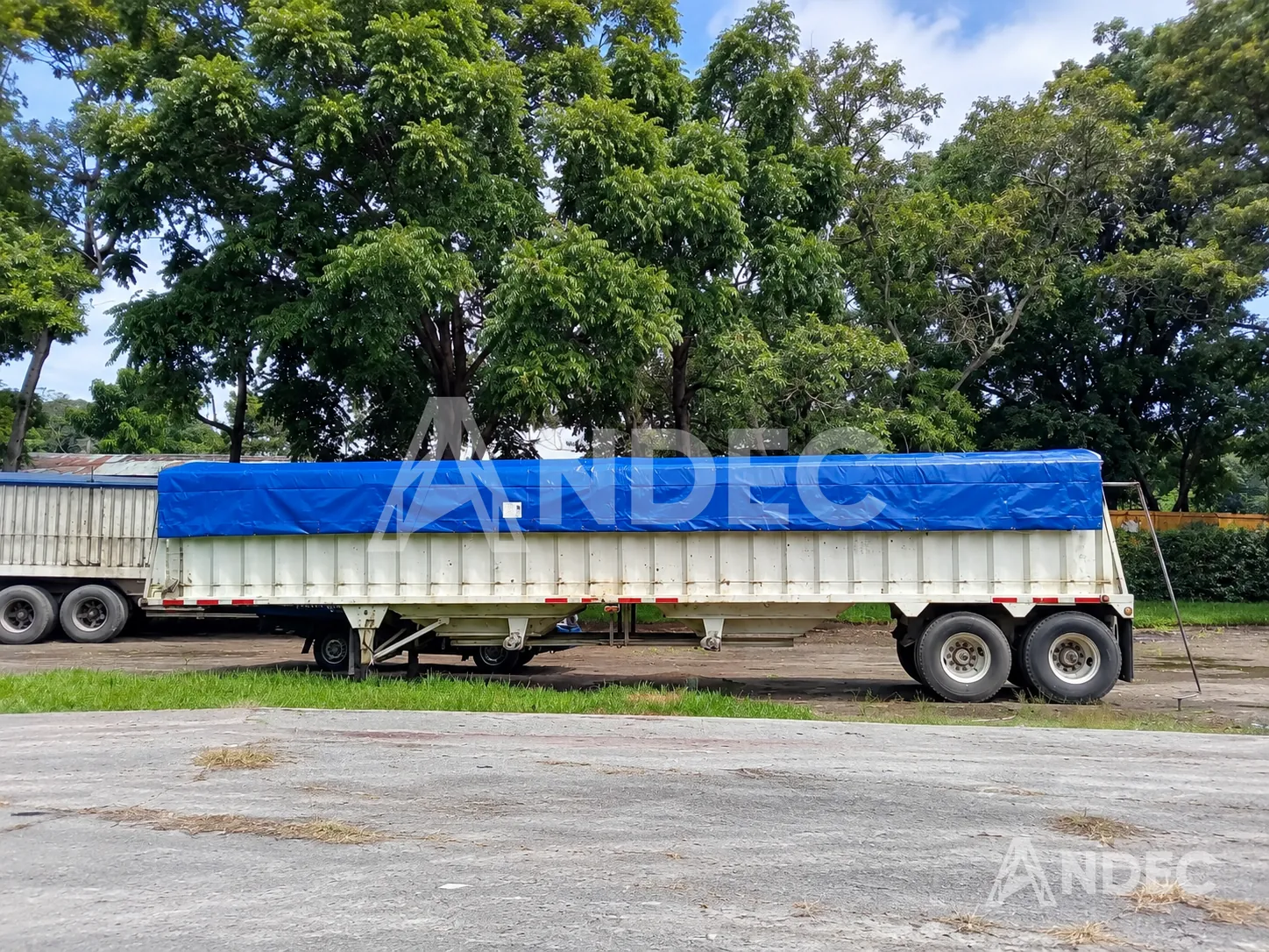 Cobertor de lona PVC azul tensado sobre un semirremolque de carga a granel con barandas altas
