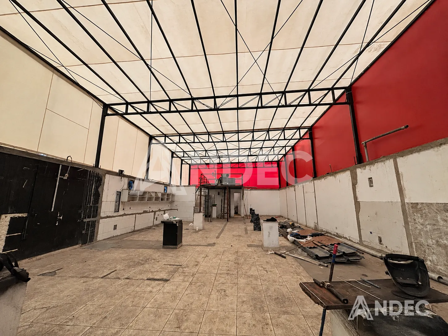 Cobertura industrial de almacén en lona PVC: techo translúcido y paredes rojas sobre estructura metálica