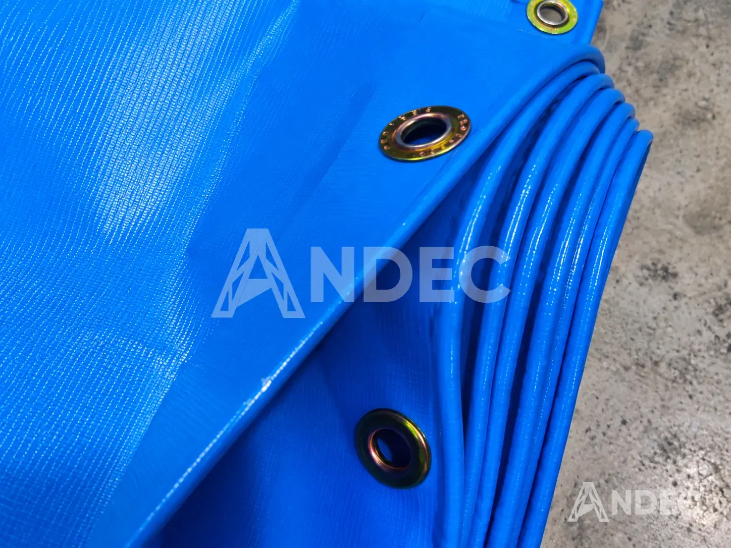 Detalle del ojal metálico perimetral en un toldo de lona PVC azul