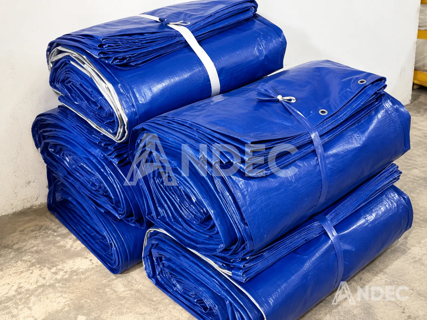 Lote de toldos de lona PVC azul plegados y atados, listos para despacho